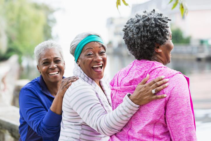 Three senior women laughing together outdoors