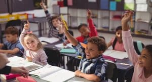 Schoolkids raising their hands in class