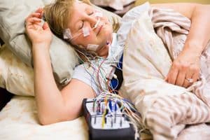 Woman sleeping in a bed in the hospital with equipment attached during a sleep study