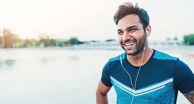 Man smiling with headphones in after running