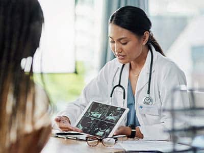 Female doctor pointing to a table with scan results explaining treatment options for spina bifida