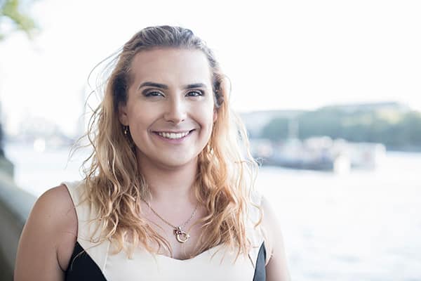 Transgender woman smiling with a body of water in the background