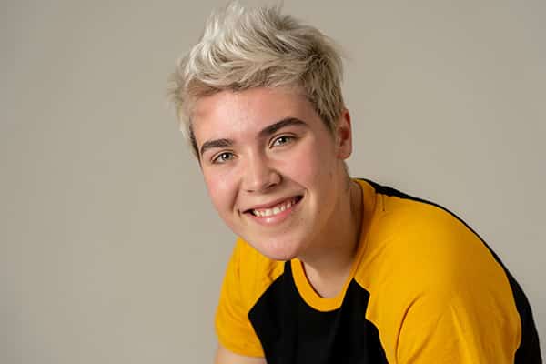 Transgender man in a yellow shirt smiling