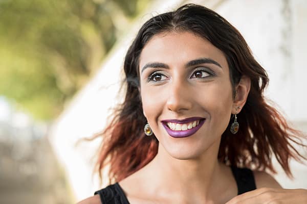 Transgender woman with purple lipstick smiling