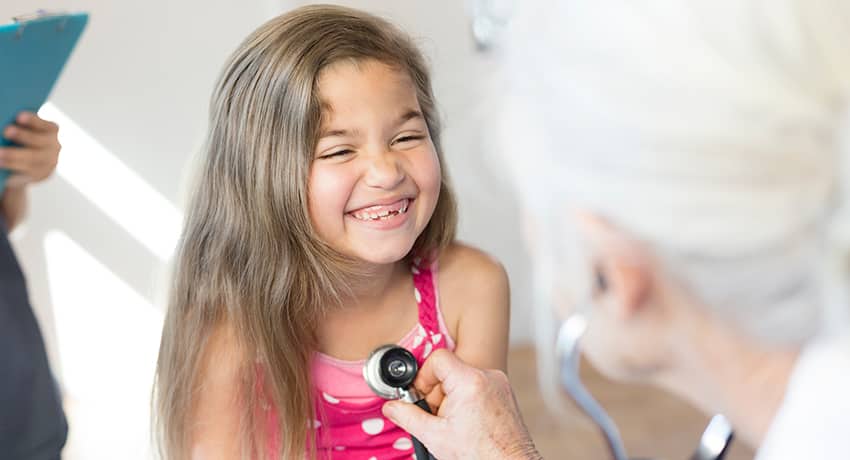 Doctor checking little girl's heartbeat