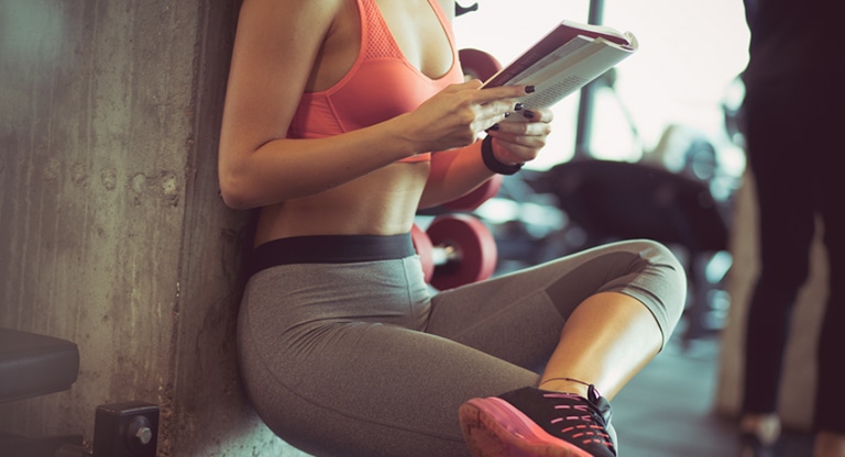 A women reads a book during her workout break