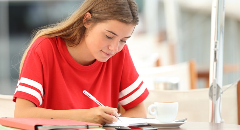 A teen drinks coffee as she studies