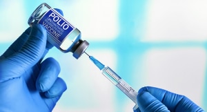 A syringe is inserted into a vile of polio vaccine