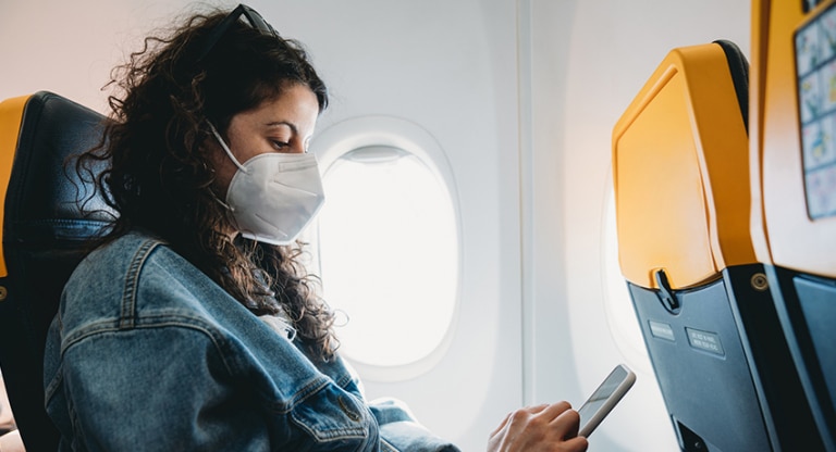 Female traveling on plane wearing a mask