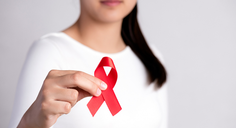 Woman holds up HIV Awareness Month ribbon