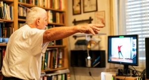 Senior man exercises to exercise video at his home