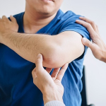 Doctor inspecting a man's elbow during a checkup