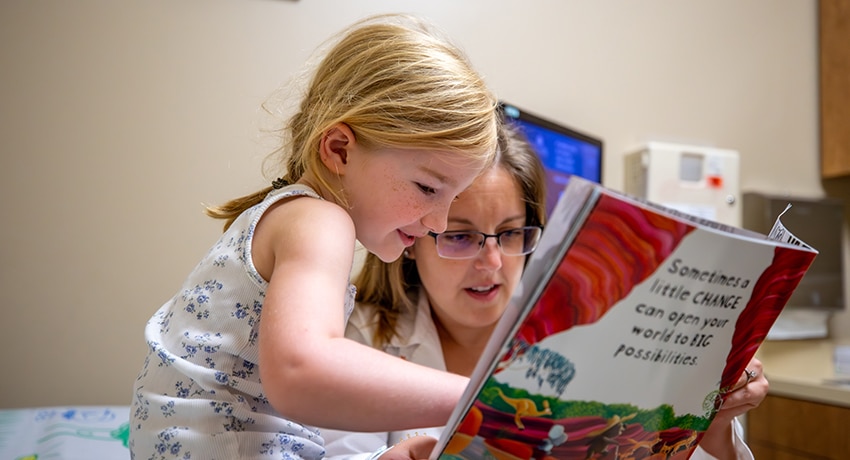 Child and adult reading a book