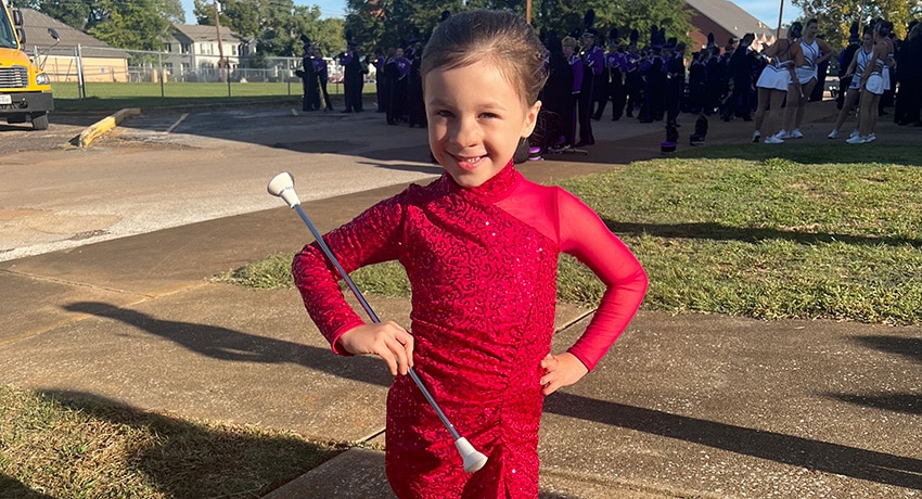 Young girl in red outfit holding a baton.