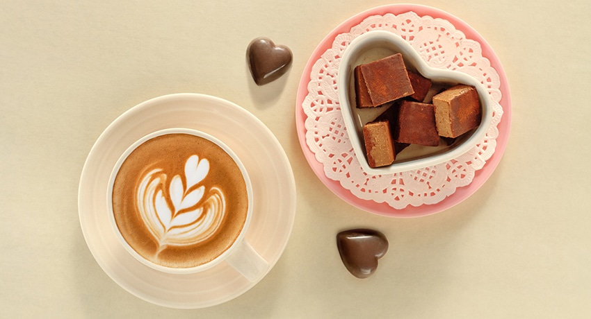 Raw cube chocolate pieces and coffee with heart-shaped latte art.