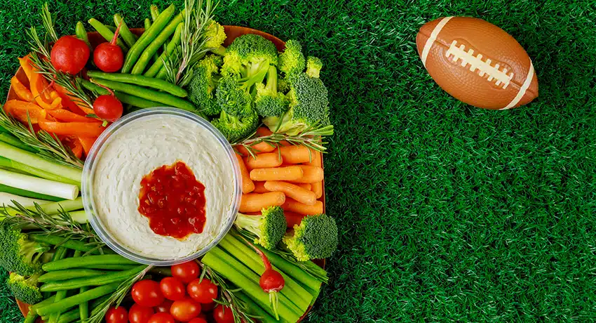Healthy snack recipes like a vegetable platter with football ball for american football game party.