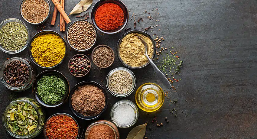 Colorful herbs and spices for cooking. Indian spices. On grey stone background. Top view.