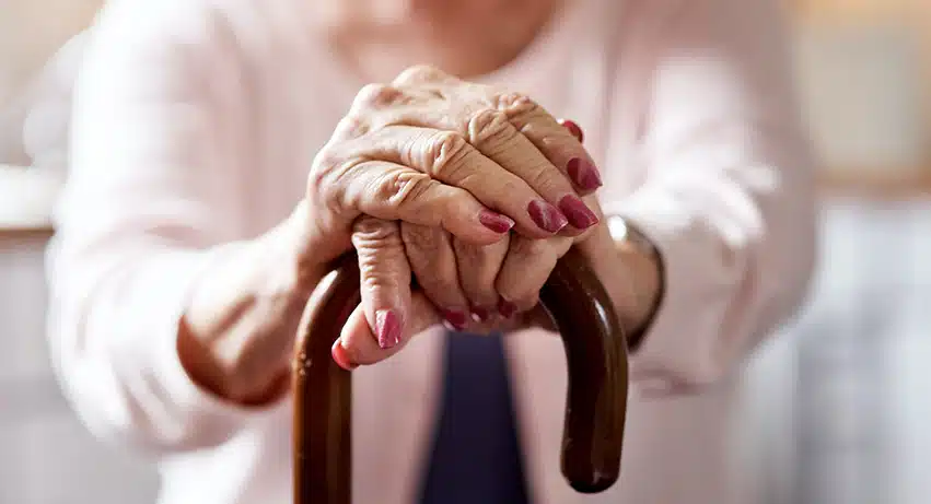 Elderly woman's hands gripping a walking cane