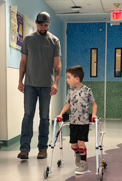 Brantley in therapy walking with his father