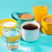 Multicolored mugs with drinks on a blue background side view.