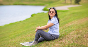 Angel Nguyen sitting on the banks of a lake as pediatric stroke survivor