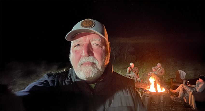 David Fish camping with friends, camp fire in the background