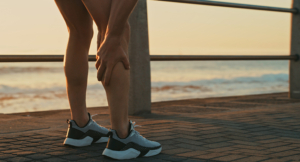 Man holding his leg in pain while exercising along the promenade