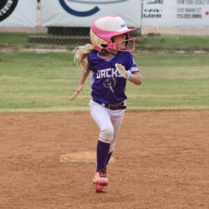 Ellie running on the baseball field in uniform