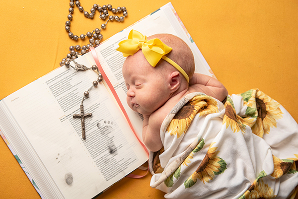 Rylan posed sleeping on a bible, rosary placed next to her