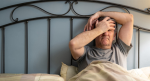 Man with difficulty sleeping sitting on the bed and with a gesture of despair