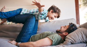 A father playing with his son on the sofa at home