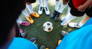 Team Huddle Around Soccer Ball on Field