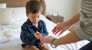 Child sharing warmth with his mom rubbing his hands on cozy bed