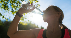 women drinking water outside in the sun to stay hydrated