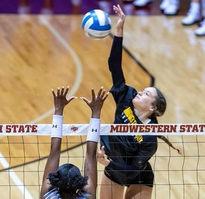 Koryn jumping to spike the volleyball at the net