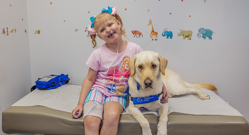 Boris the dog and Elainafaith smiling in a clinic exam room