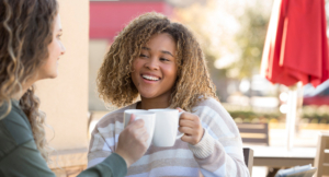 Two teenage girls enjoy an afternoon break at a sidewalk cafe with coffee mugs